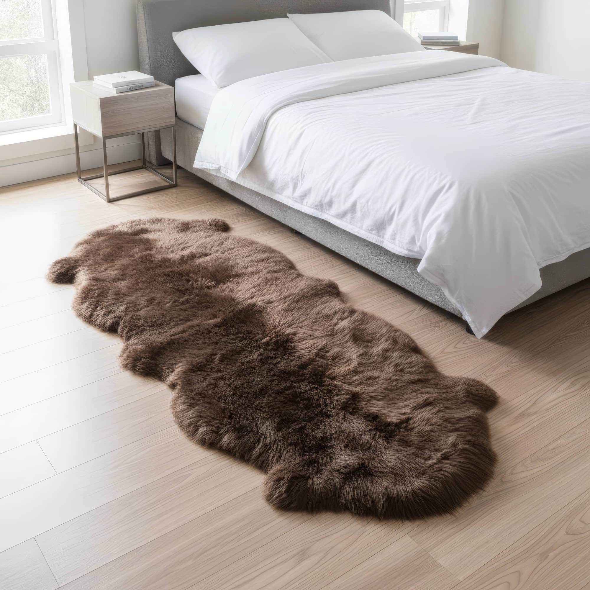 Brown fur rug on a wooden floor in a bedroom with white bedding. #size_2' x 6'