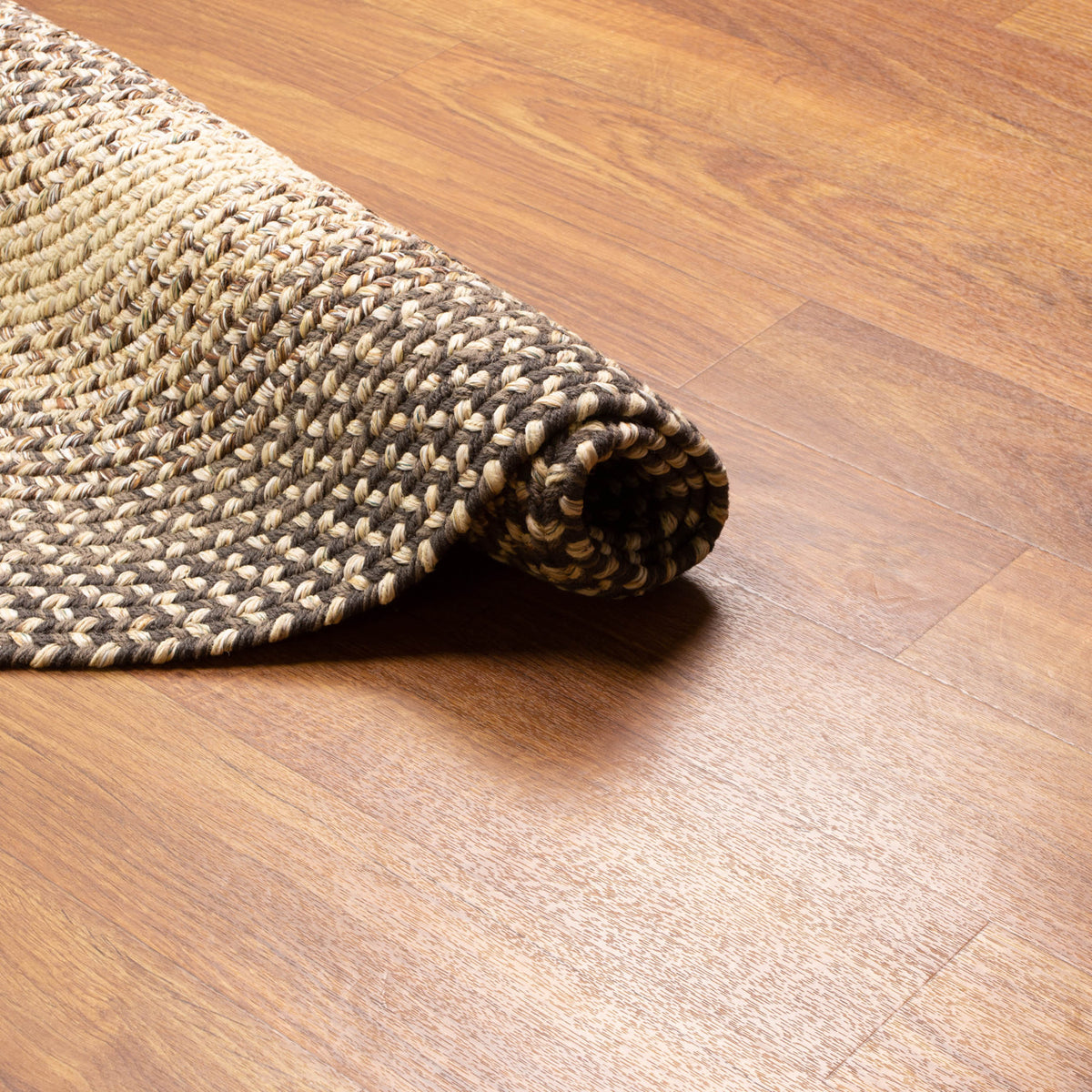 Ridgewood brown braided wool rug rolled, showing the flat low-profile braid