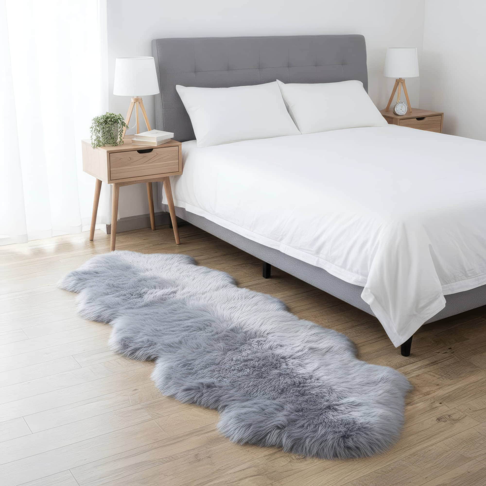 Gray fur rug on a wooden floor in a bedroom with a bed and nightstands. #size_2' x 6'