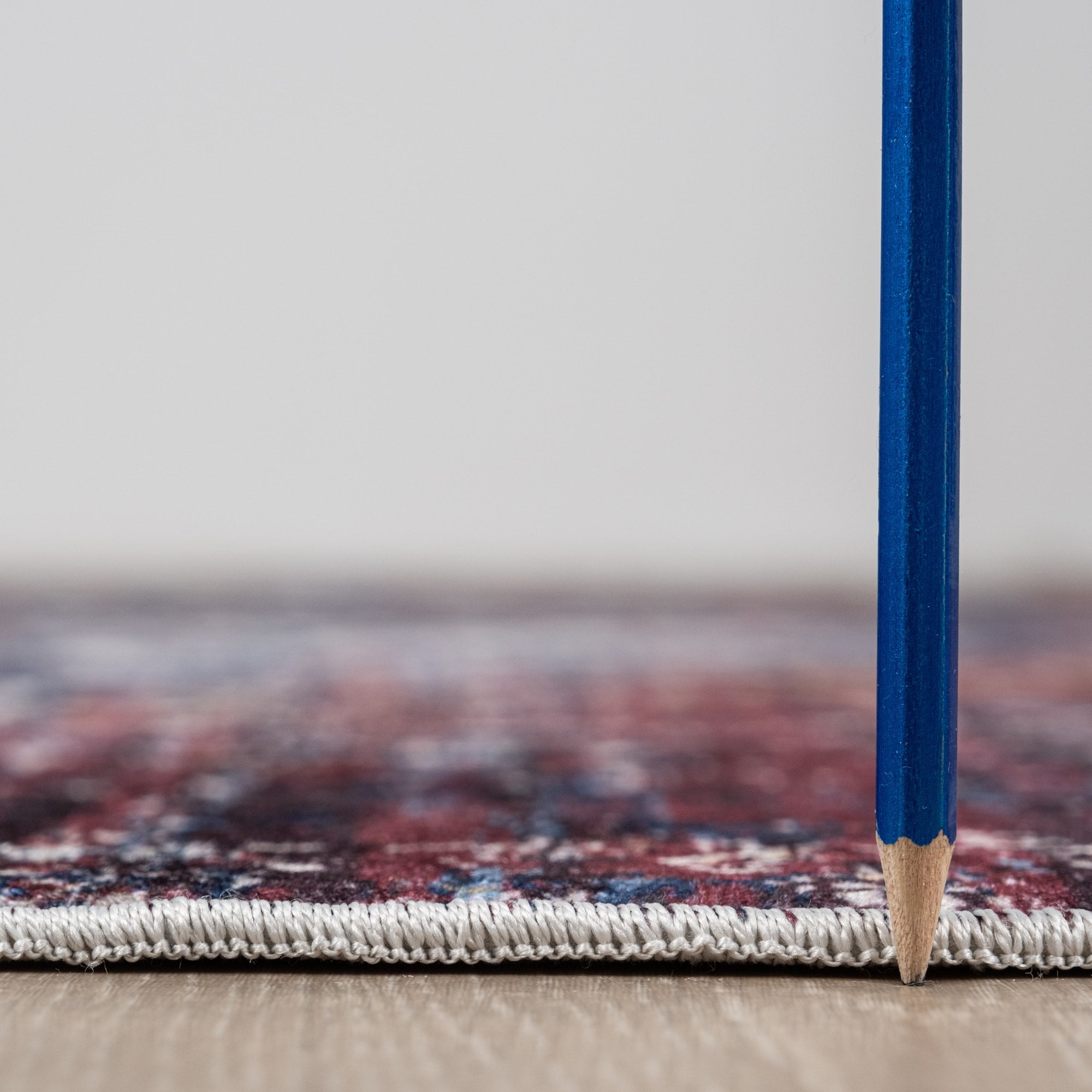 Red Bursa machine washable area rug 4' x 6' - low pile height next to a pencil