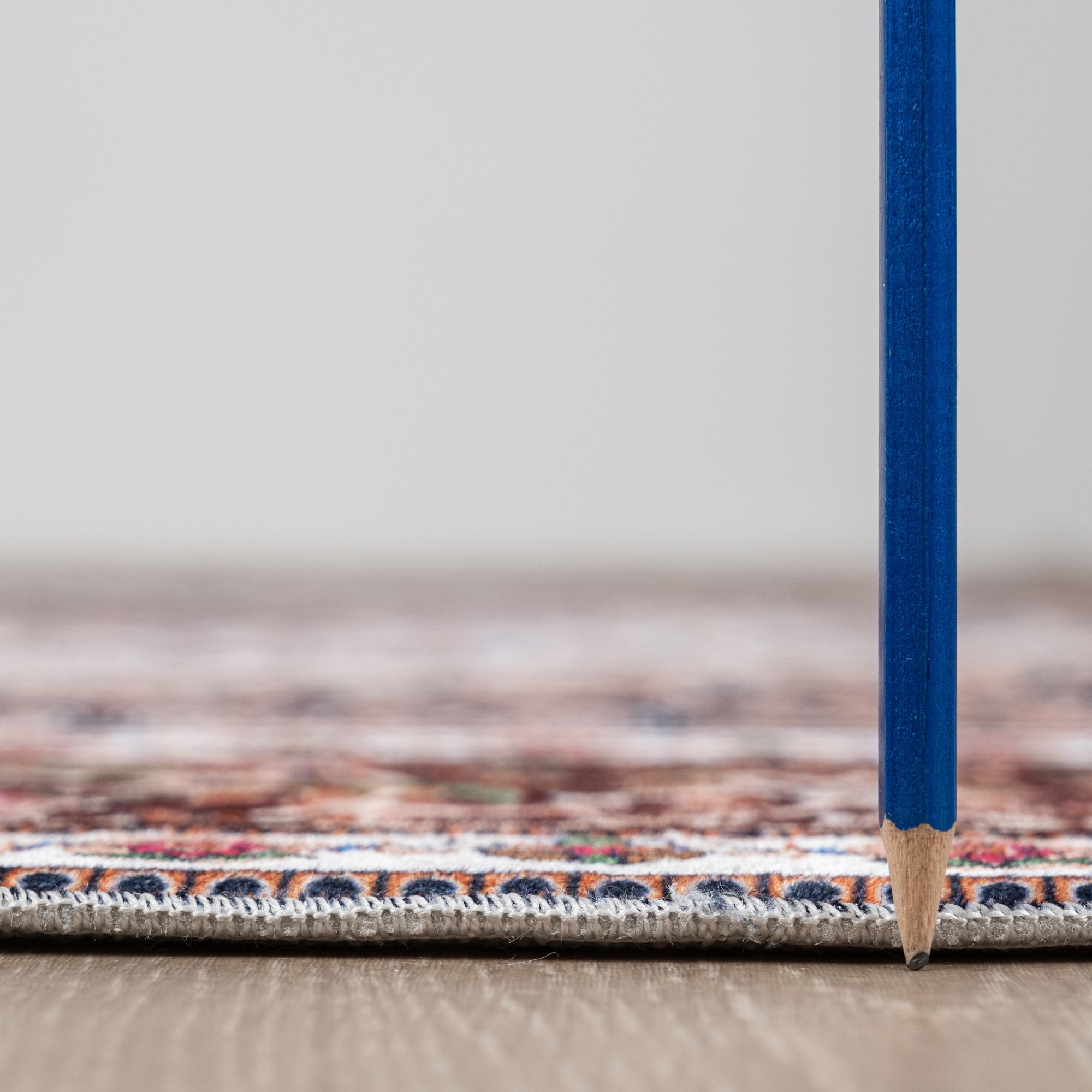 Red / Navy Bursa machine washable area rug 2' x 3' - low pile height next to a pencil