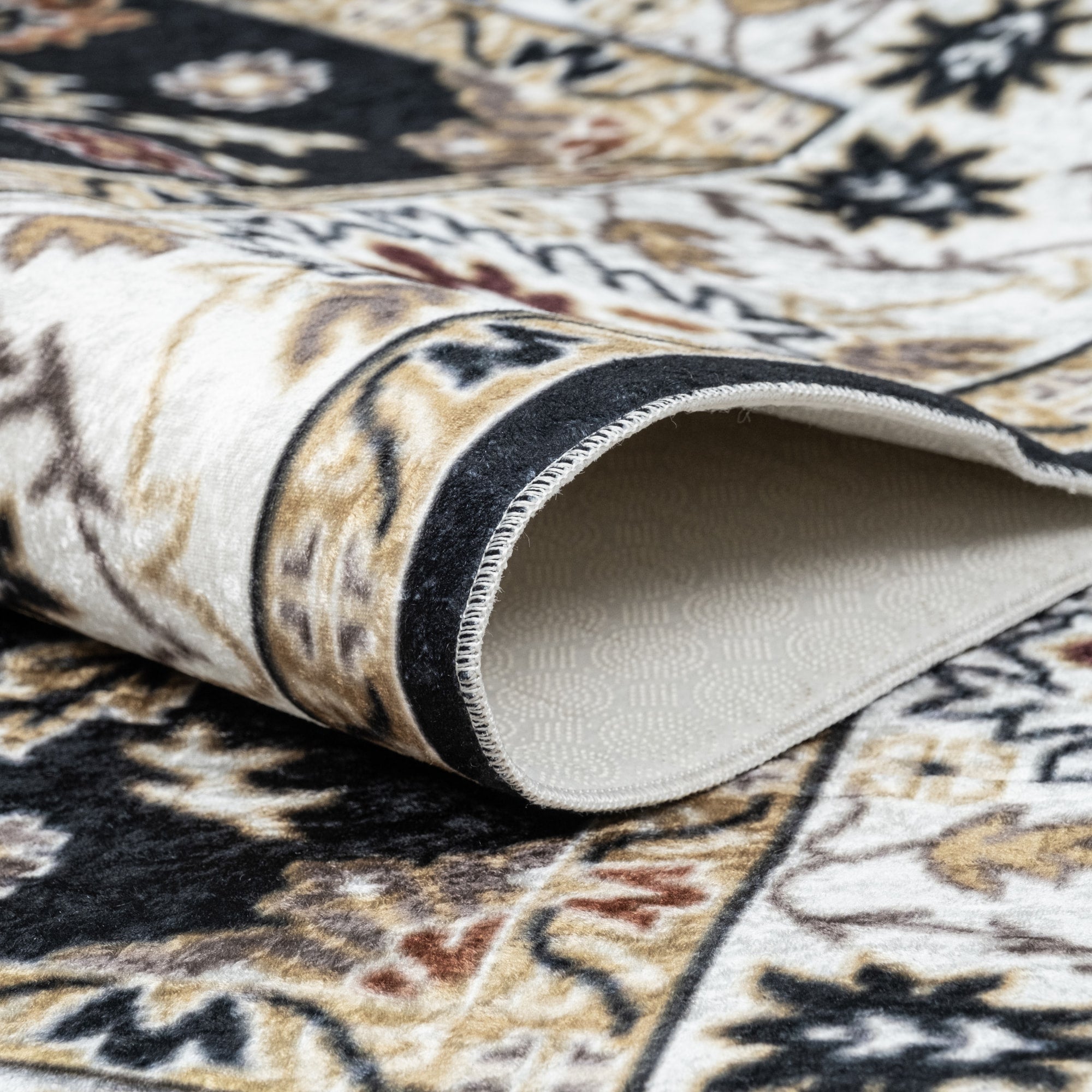 Black Bursa machine washable area rug 4' x 6' - folded to show the non-slip backing