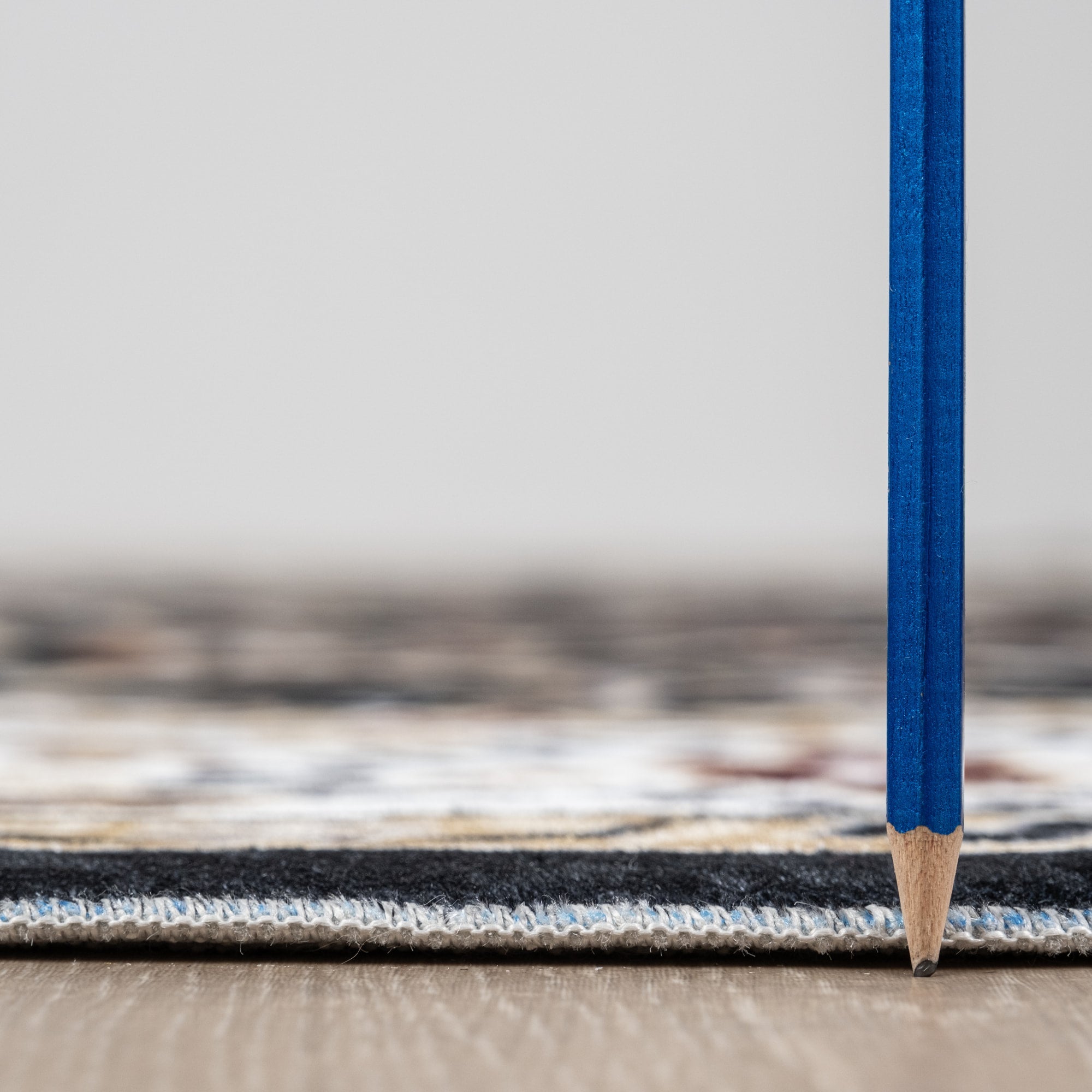 Black Bursa machine washable area rug 4' x 6' - low pile height next to a pencil