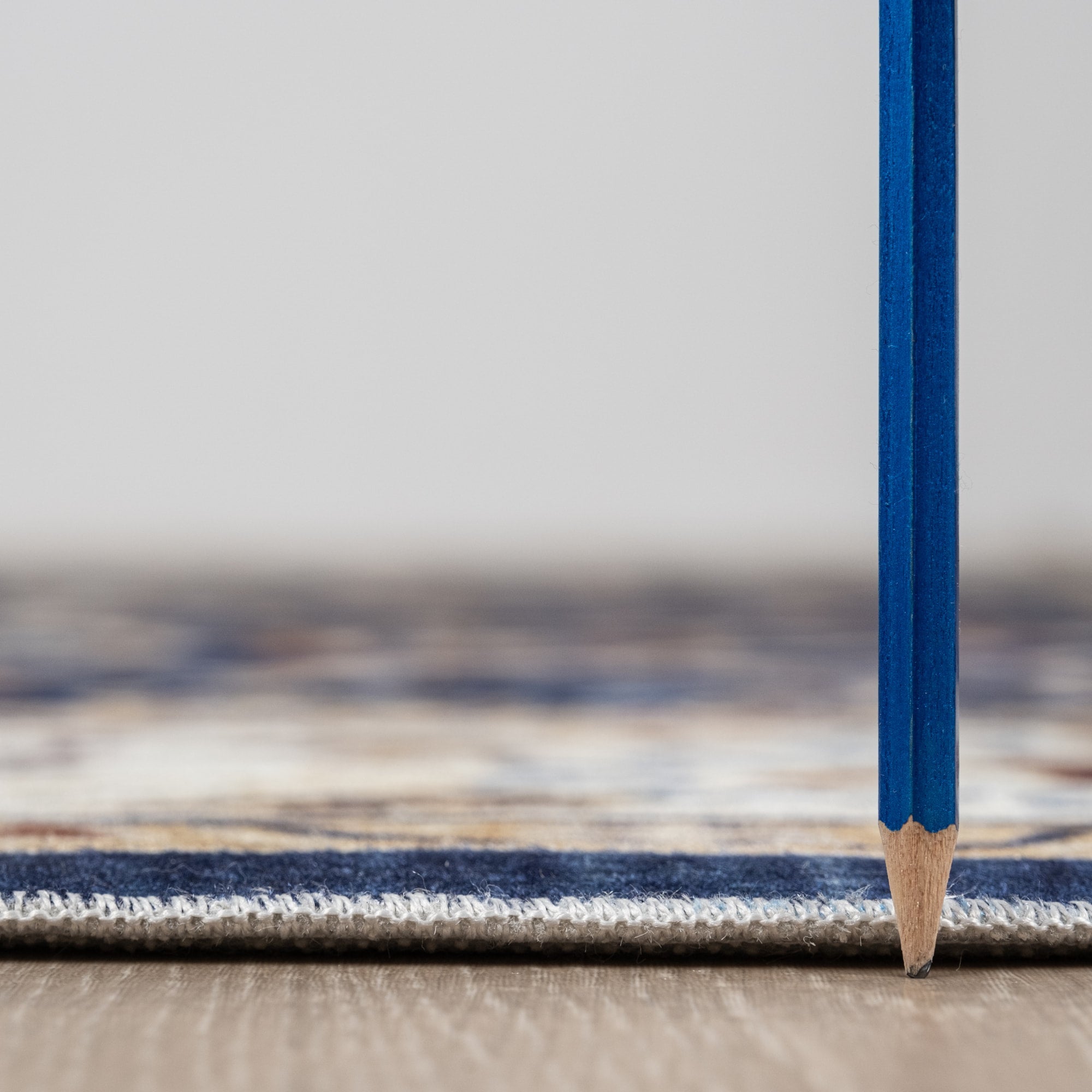 Navy Bursa machine washable area rug 4' x 6' - low pile height next to a pencil
