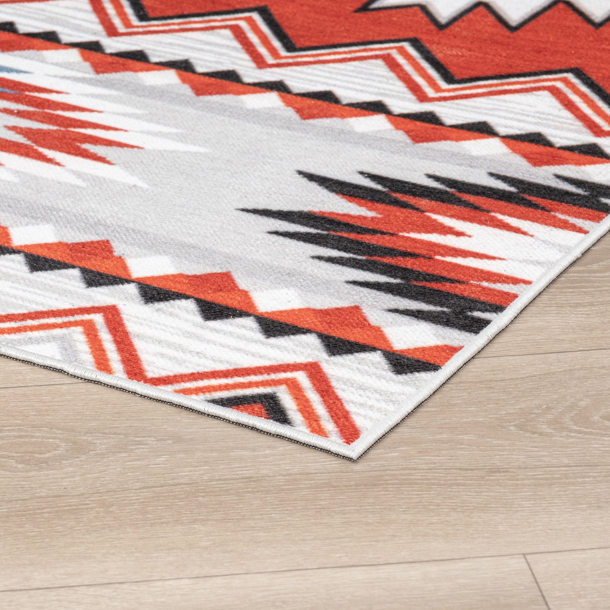Red Konya machine washable area rug 4' x 6' - corner detail on hardwood floor