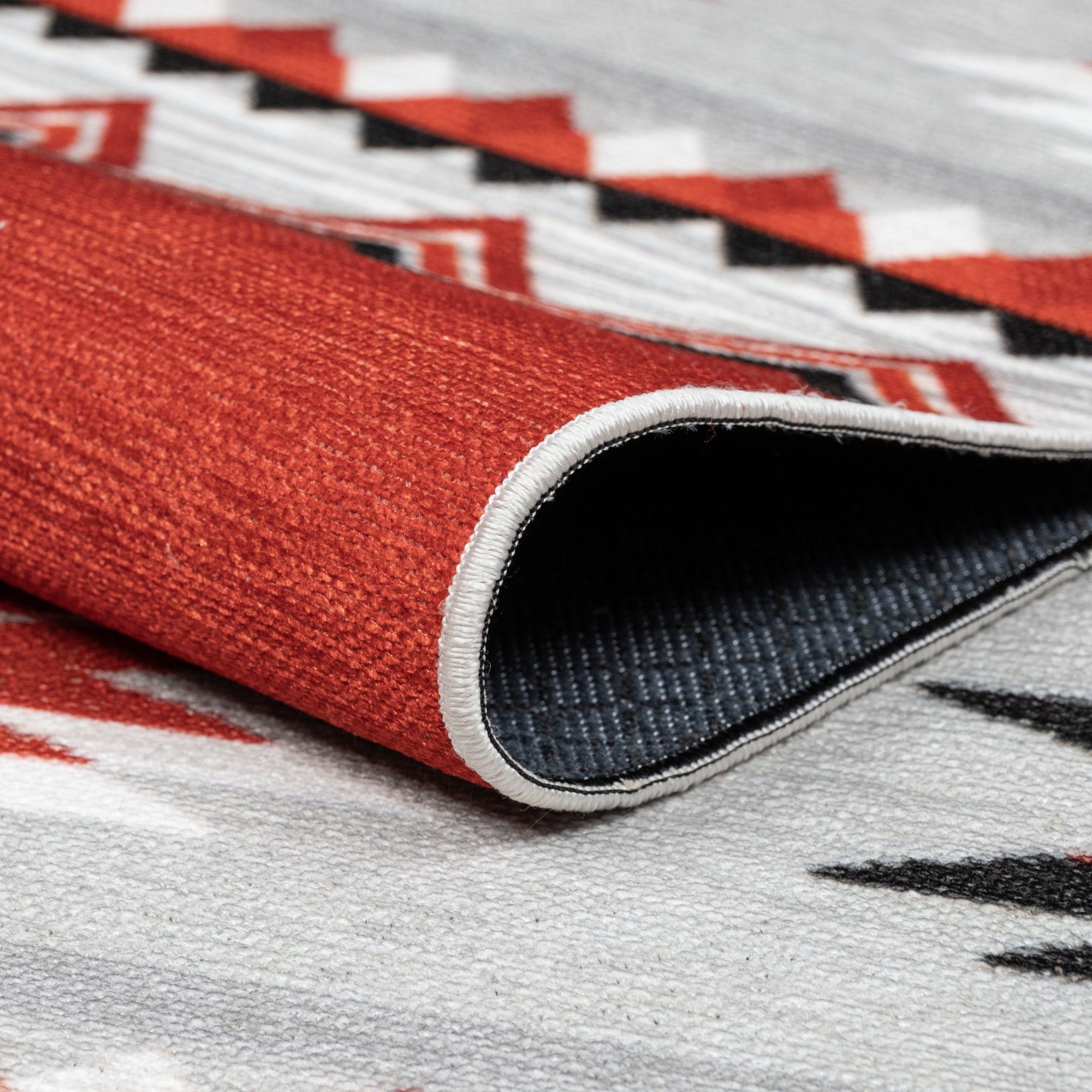 Red Konya machine washable area rug 4' x 6' - folded to show the non-slip backing