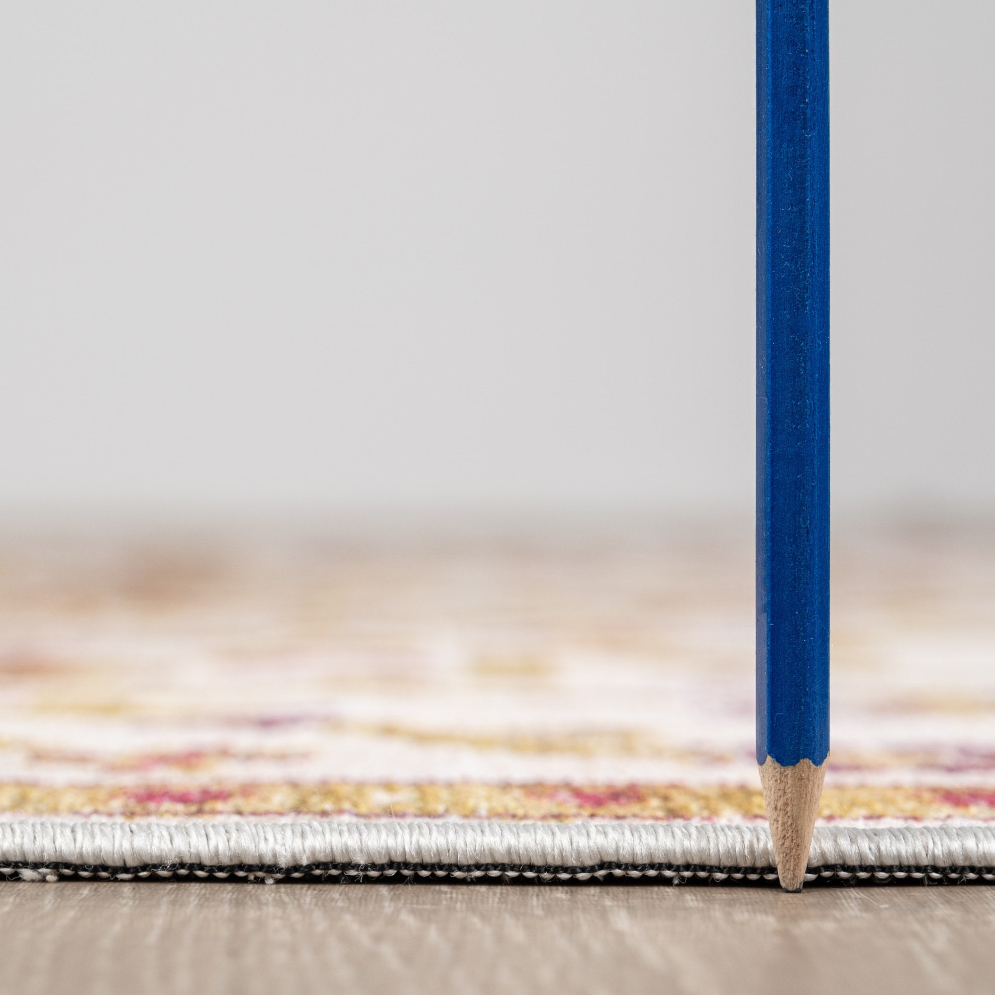 Ivory Konya machine washable area rug 4' x 6' - low pile height next to a pencil