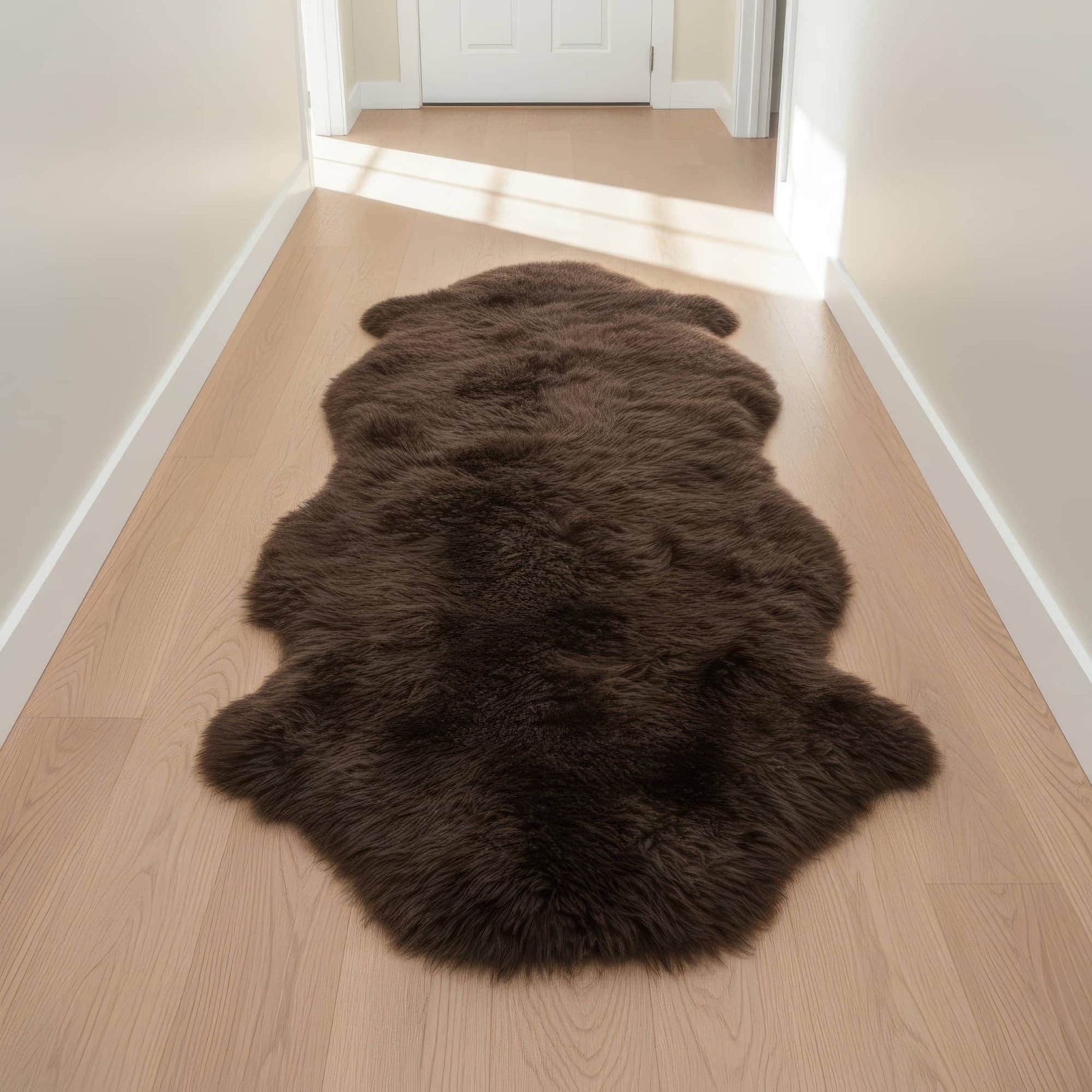 Brown fur rug on a wooden floor in a room with white walls and a door. #size_2' x 6'