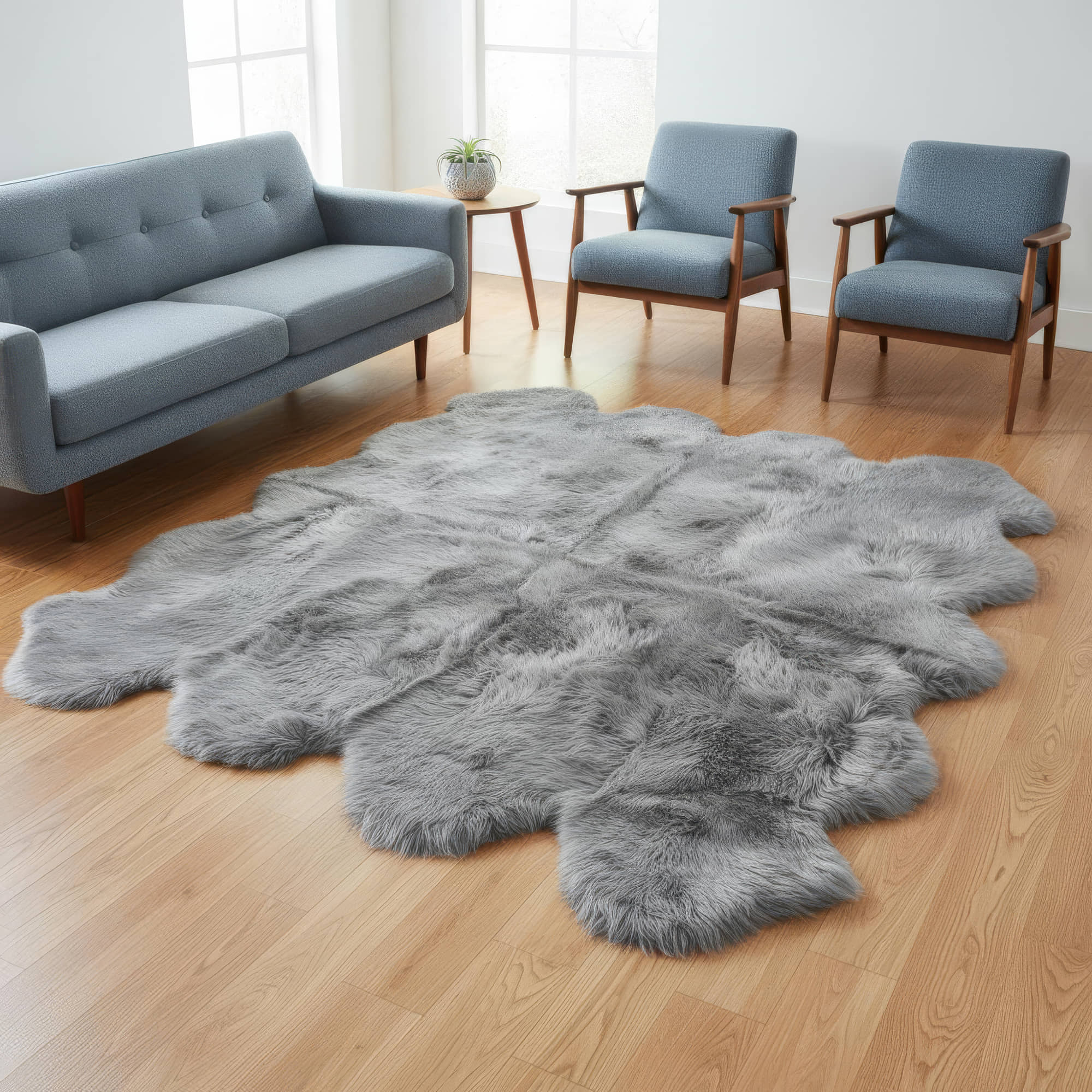 Gray fur rug on a wooden floor with a sofa and chairs in the background.  #size_6' x 7'