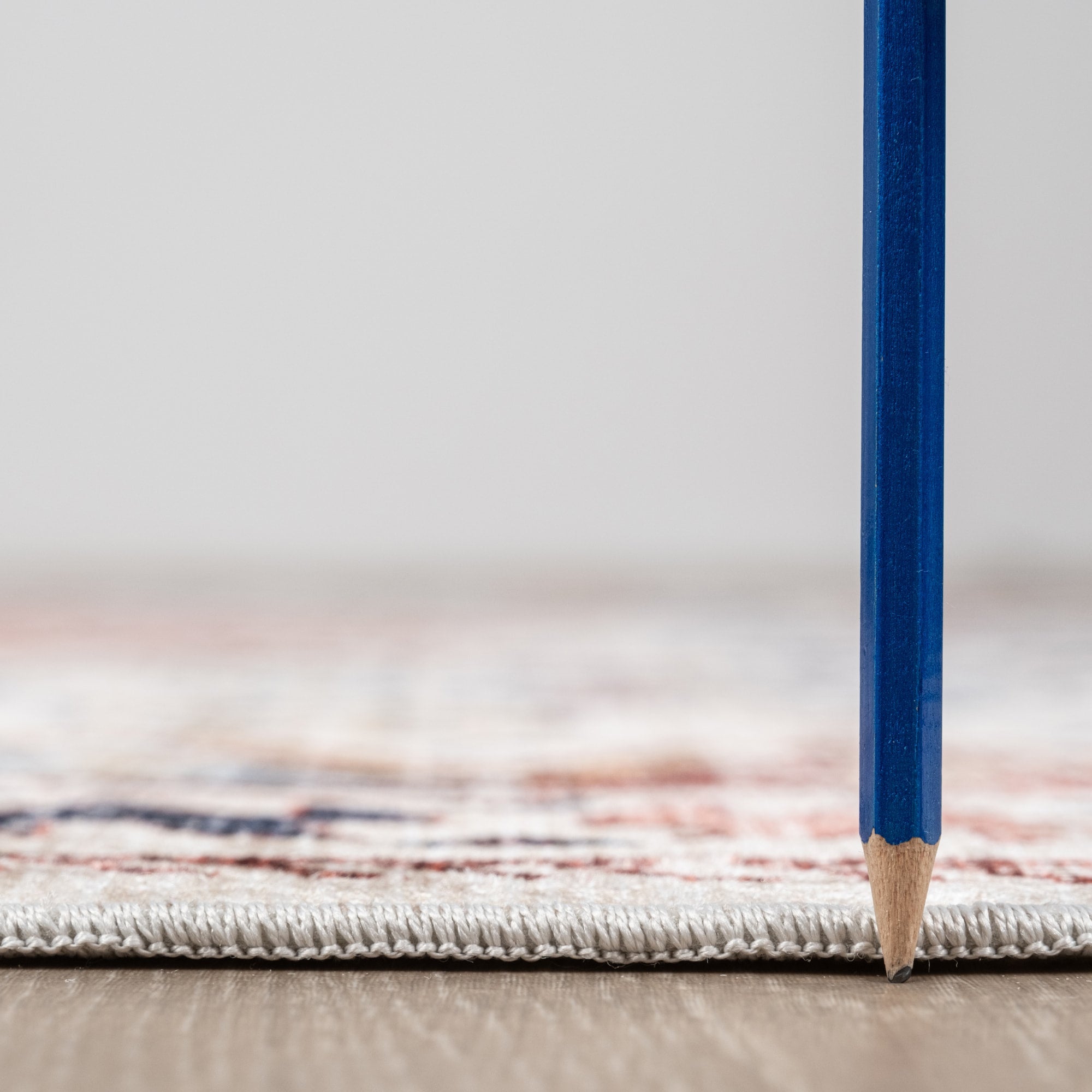 Pastel Bursa machine washable area rug 5' x 7' - low pile height next to a pencil