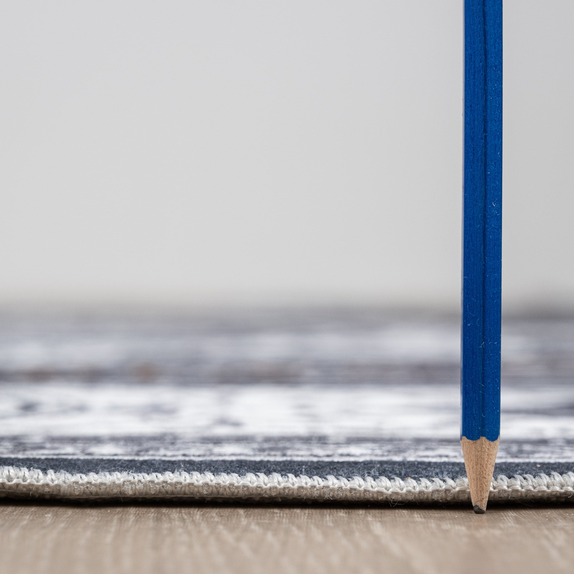 Gray Bursa machine washable area rug 3' x 5' - low pile height next to a pencil