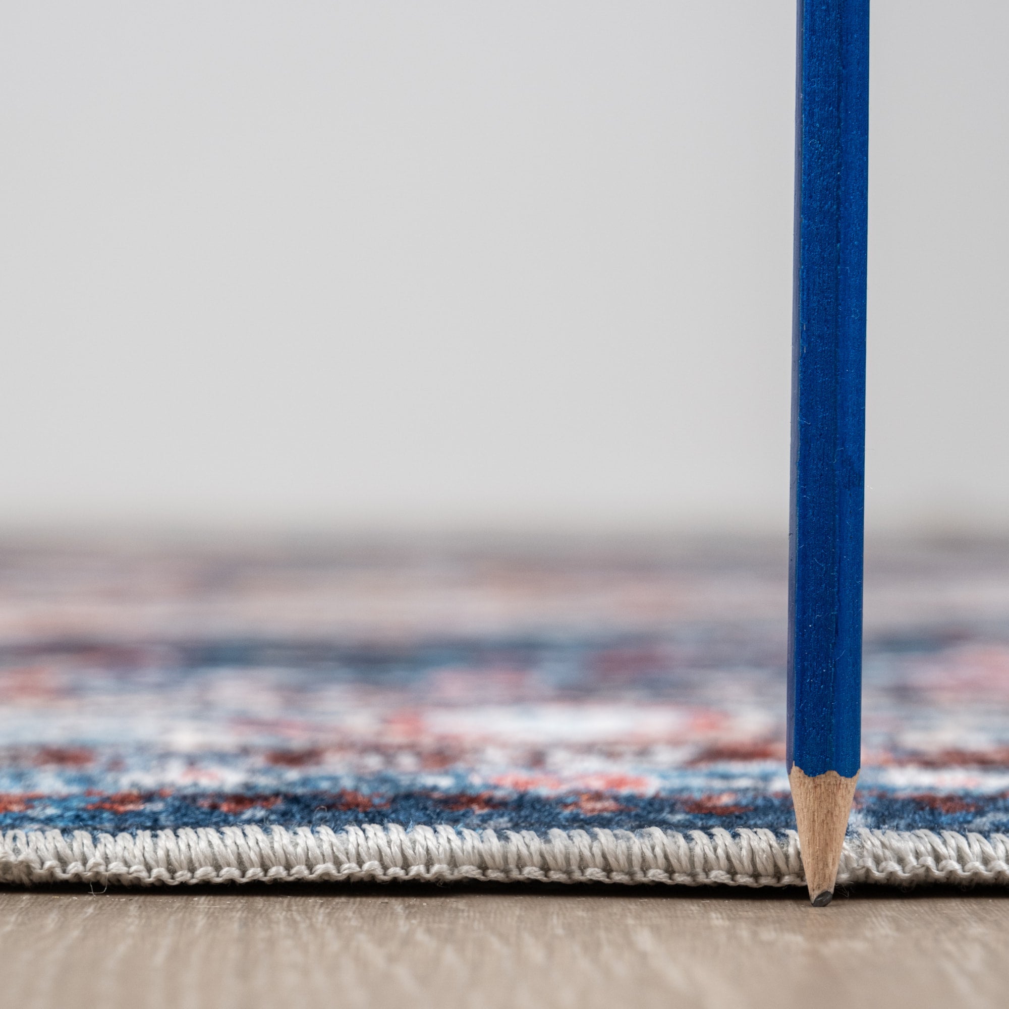 Peach Bursa machine washable area rug 4' x 6' - low pile height next to a pencil