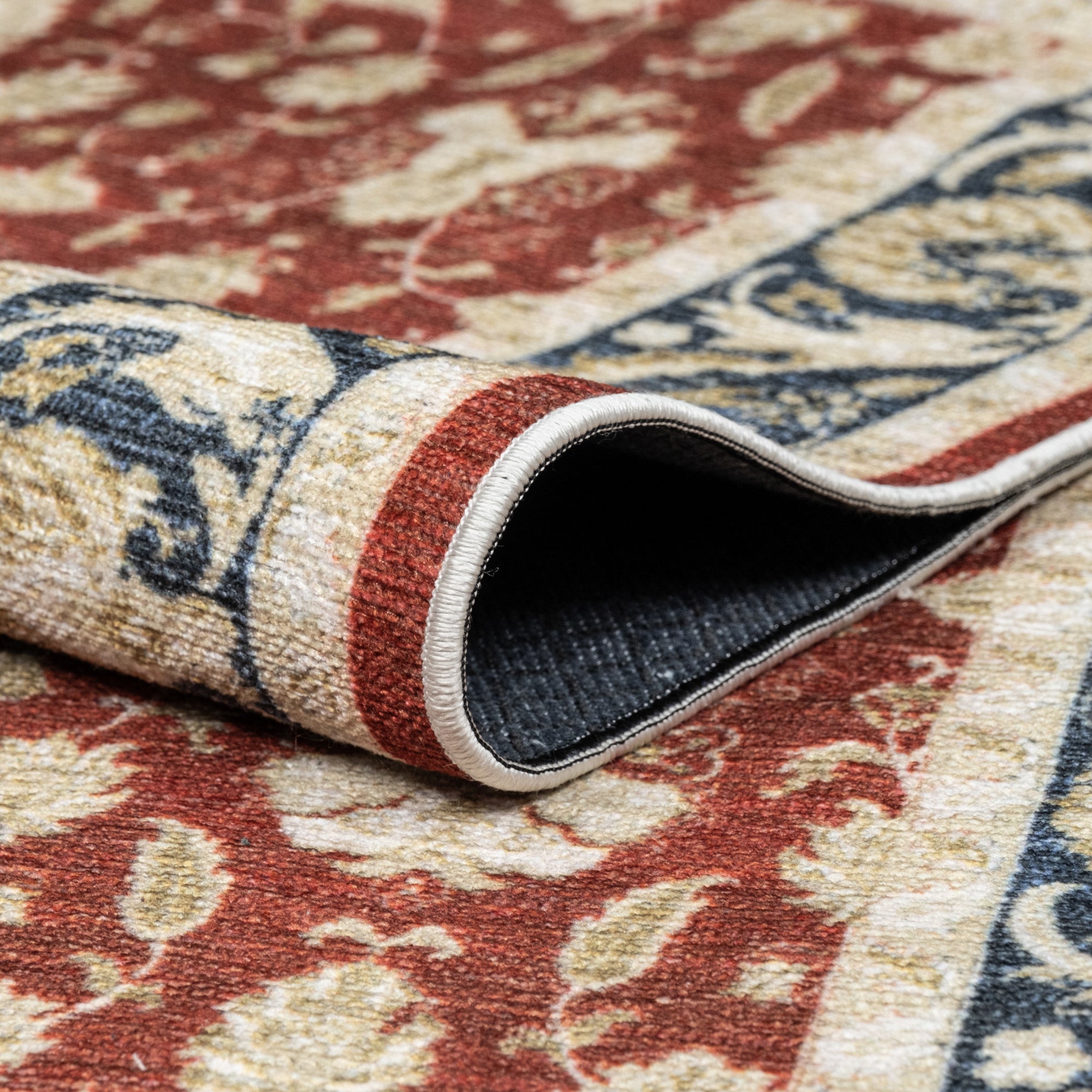 Red Konya machine washable area rug 2' x 3' - folded to show the non-slip backing