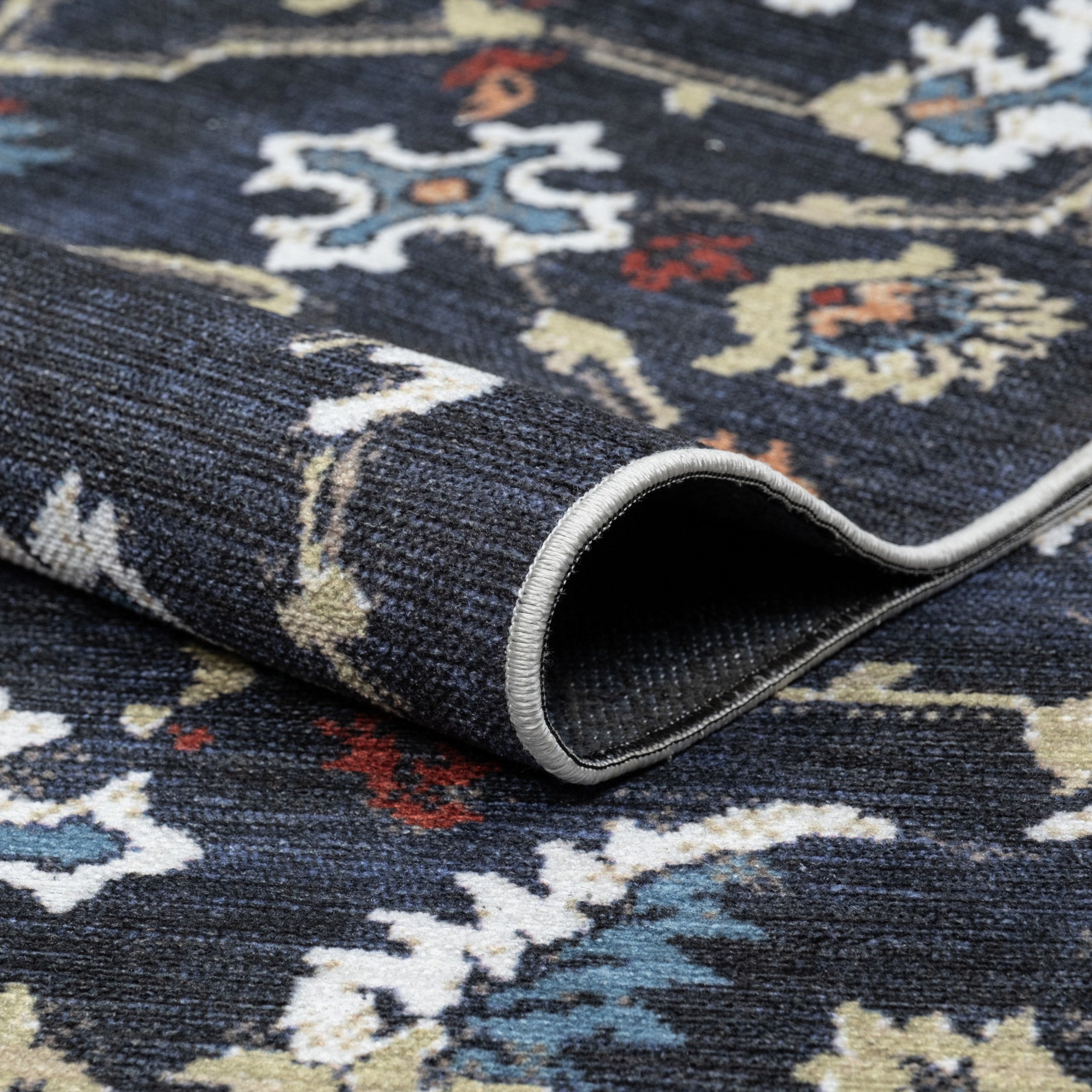 Navy Konya machine washable area rug 2' x 3' - folded to show the non-slip backing