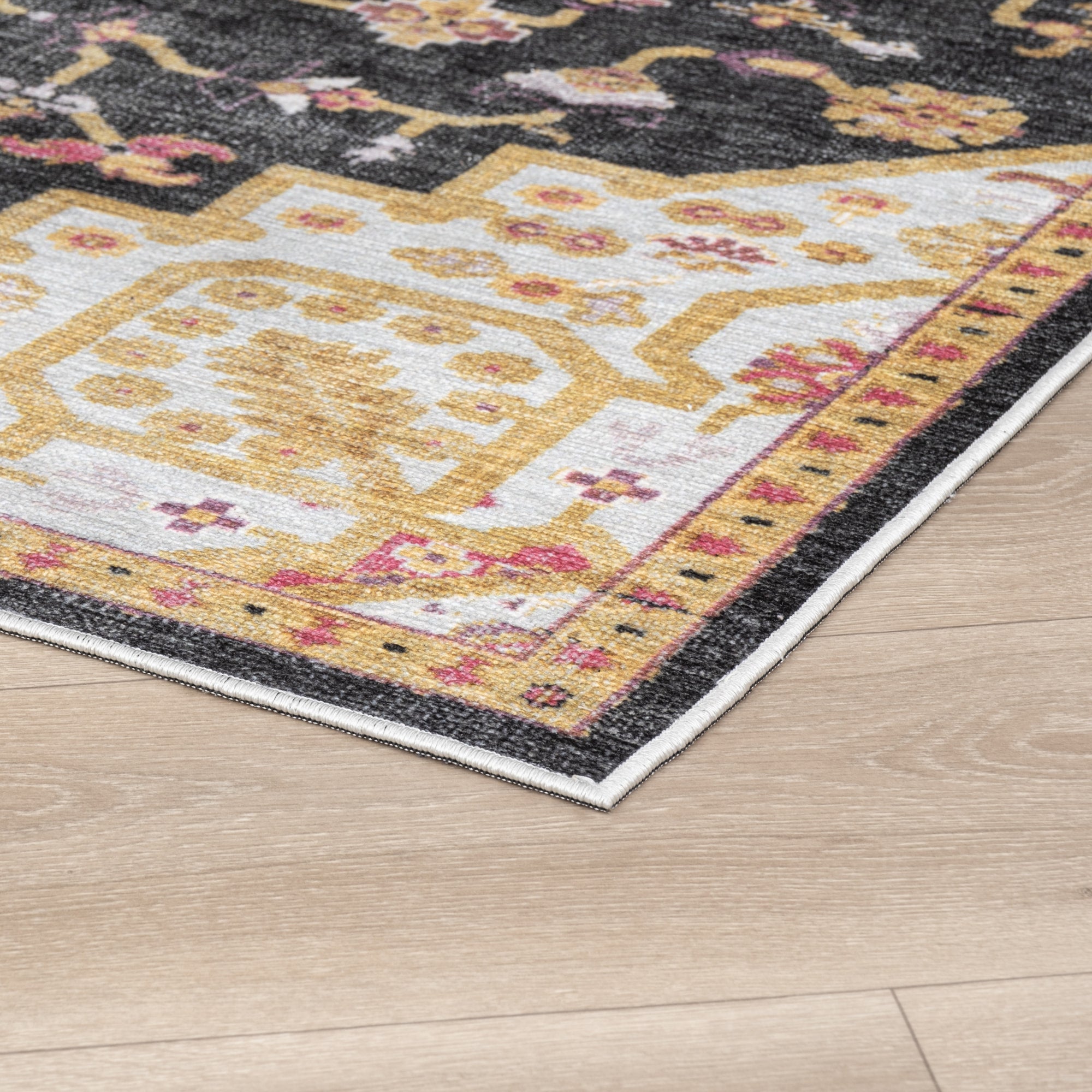 Charcoal Konya machine washable area rug 2' x 3' - corner detail on hardwood floor