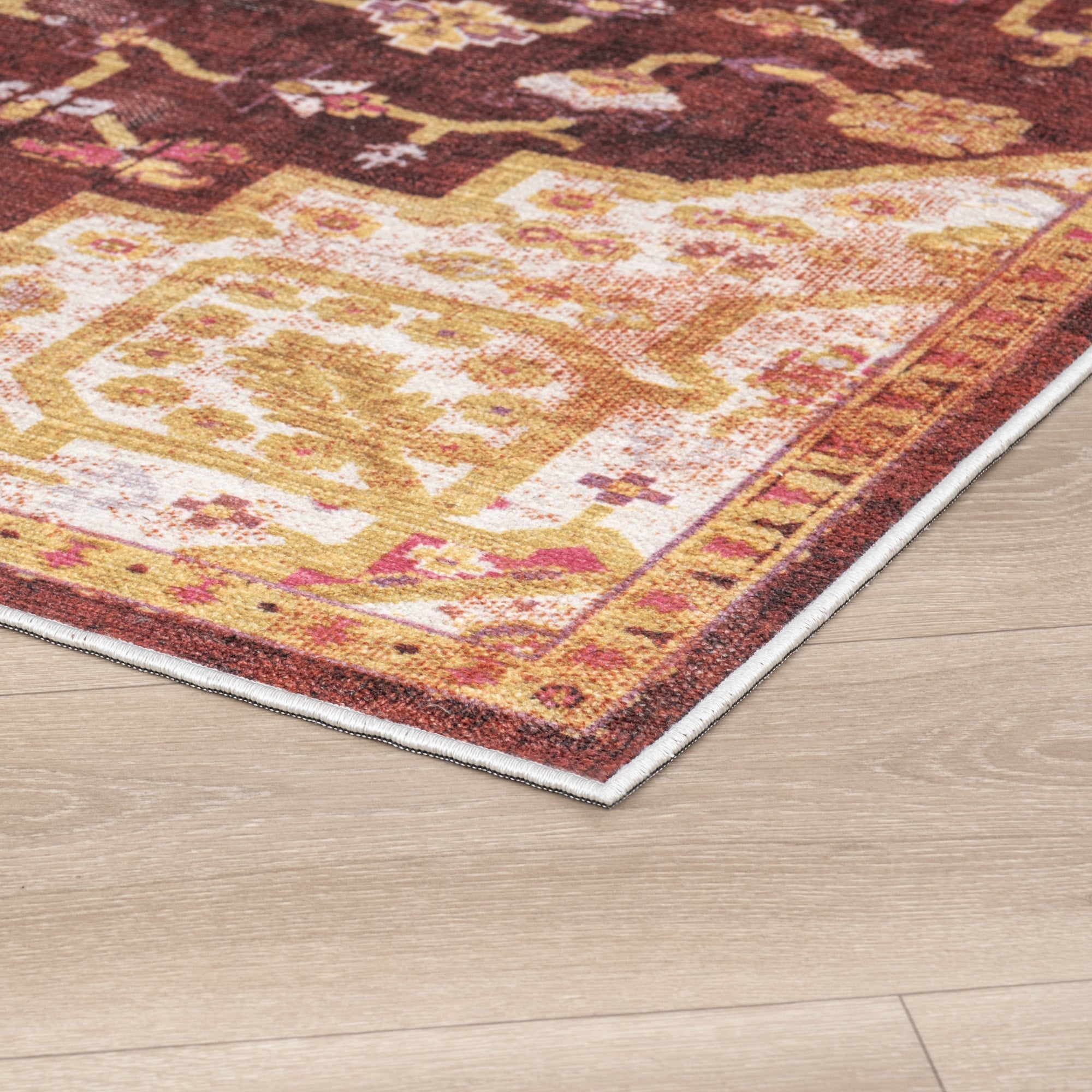 Red Konya machine washable area rug 4' x 6' - corner detail on hardwood floor