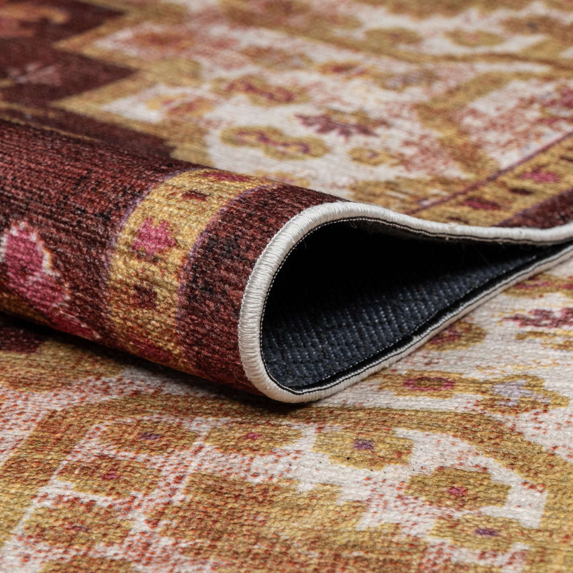 Red Konya machine washable area rug 4' x 6' - folded to show the non-slip backing