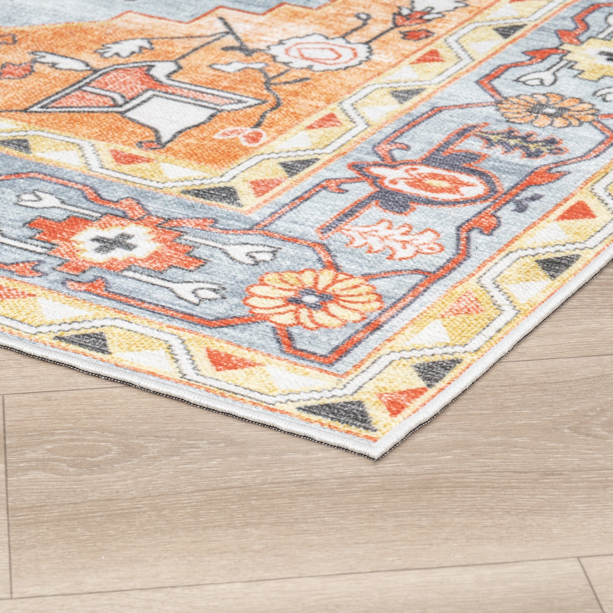 Orange Konya machine washable area rug 2' x 3' - corner detail on hardwood floor