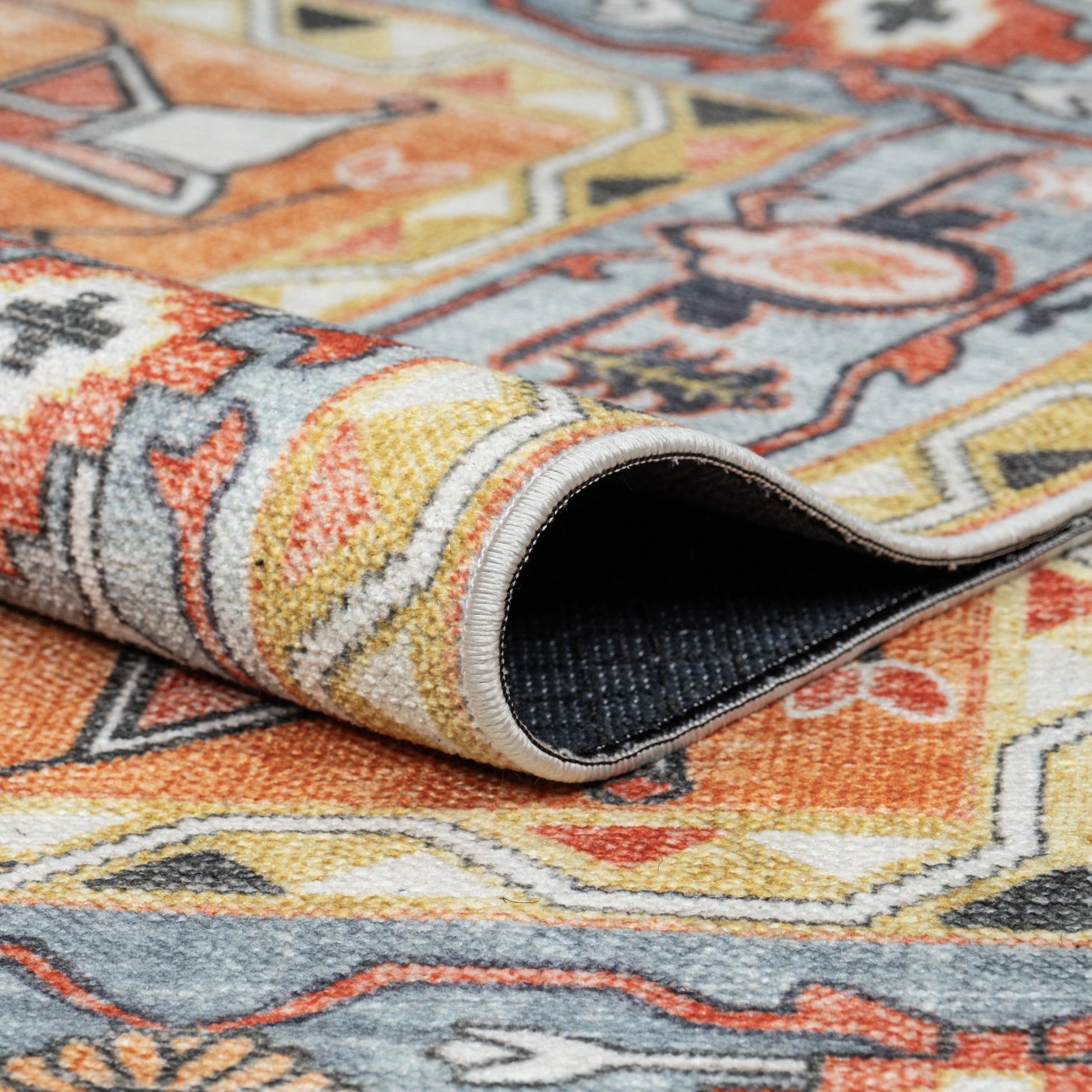 Orange Konya machine washable area rug 4' x 6' - folded to show the non-slip backing