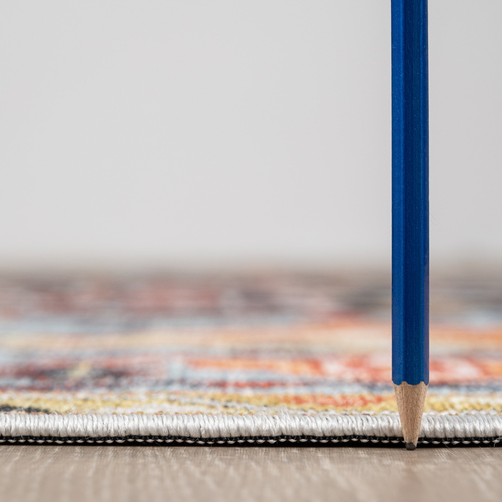 Orange Konya machine washable area rug 4' x 6' - low pile height next to a pencil